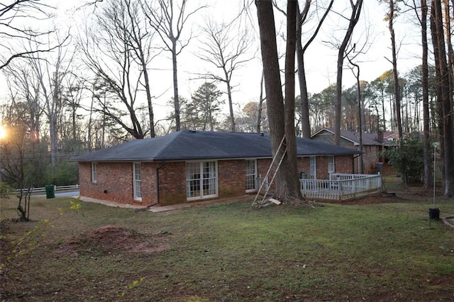 rear view of house featuring brick siding and a lawn