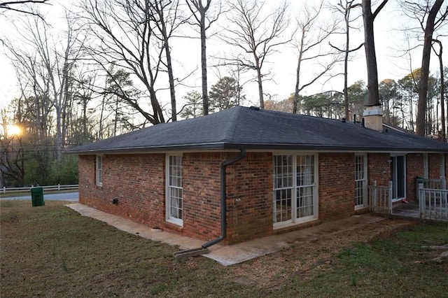 view of side of home featuring brick siding, a lawn, and a chimney