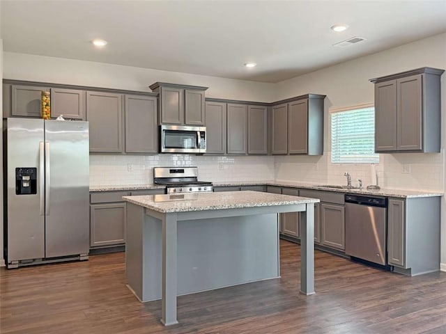 3062 Hawthorn Farm Blvd, Loganville, GA 30052 - kitchen with stainless steel appliances, gray cabinetry, decorative backsplash, a center island, and light stone countertops