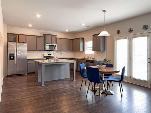 3062 Hawthorn Farm Blvd, Loganville, GA 30052 - kitchen with stainless steel appliances, gray cabinets, dark wood finished floors, tasteful backsplash, and a kitchen island