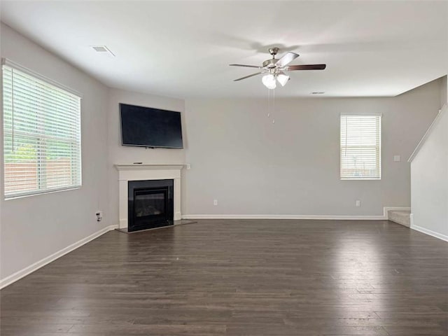 3062 Hawthorn Farm Blvd, Loganville, GA 30052 - unfurnished living room featuring ceiling fan, dark wood-style floors, a glass covered fireplace, and baseboards