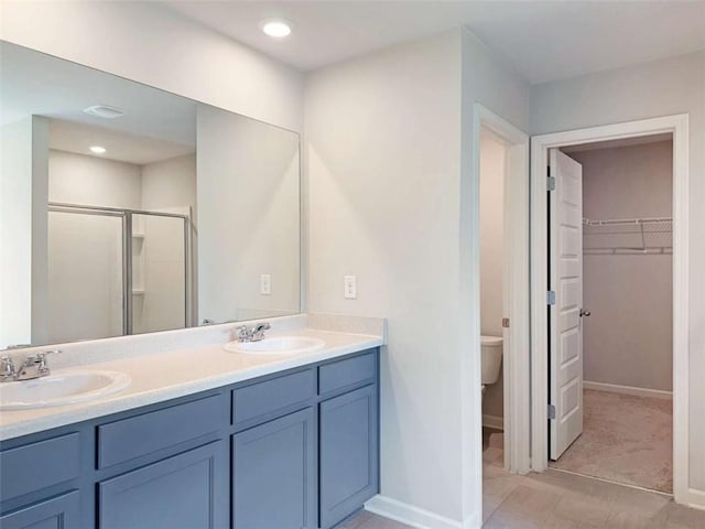 3062 Hawthorn Farm Blvd, Loganville, GA 30052 - bathroom featuring a walk in closet, double vanity, a shower stall, toilet, and baseboards