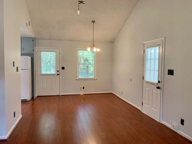 entryway with vaulted ceiling, dark hardwood / wood-style floors, and a notable chandelier