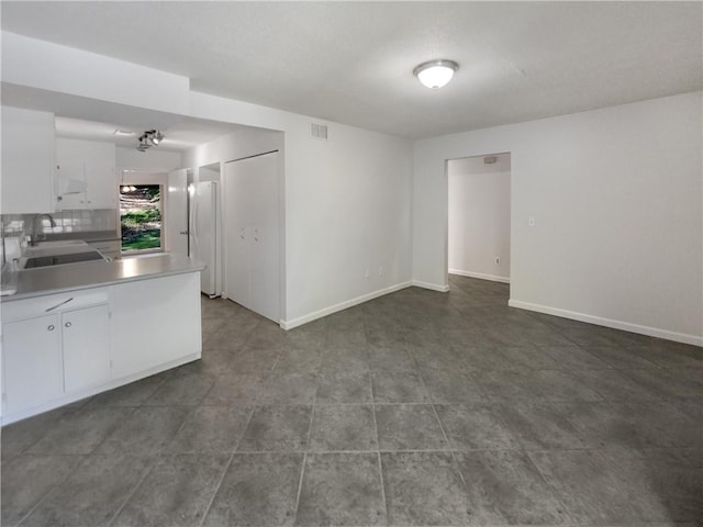 kitchen with kitchen peninsula, sink, white cabinets, and tile patterned floors