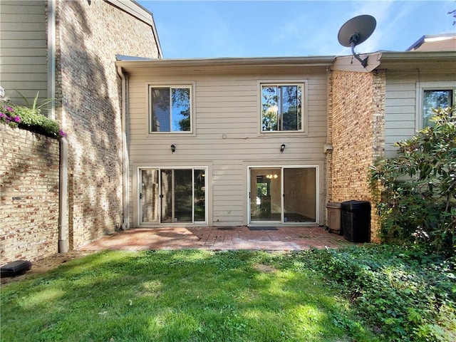 rear view of house featuring a lawn and a patio