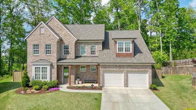 traditional home featuring fence, a front yard, roof with shingles, brick siding, and concrete driveway
