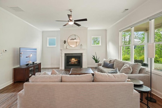 living room featuring baseboards, crown molding, visible vents, and a healthy amount of sunlight