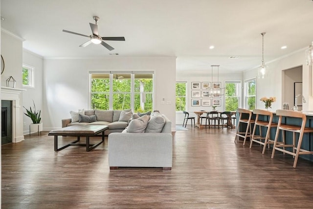 living area featuring crown molding, a ceiling fan, and a healthy amount of sunlight