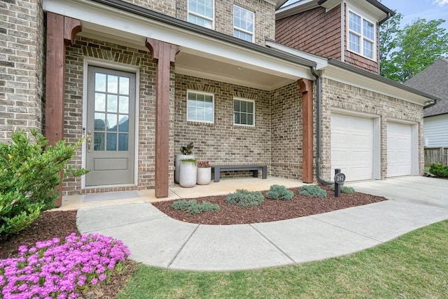doorway to property with a garage, concrete driveway, and brick siding