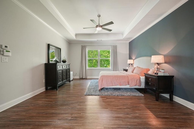 bedroom featuring crown molding, a raised ceiling, baseboards, and wood finished floors