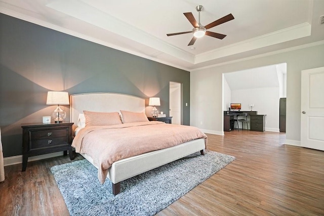bedroom with visible vents, wood finished floors, a raised ceiling, baseboards, and ornamental molding