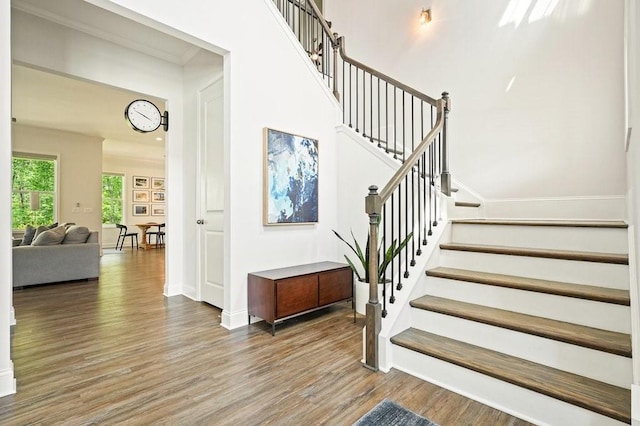 staircase with baseboards, a high ceiling, and wood finished floors