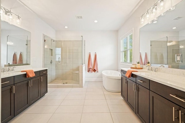 full bath featuring tile patterned floors, a freestanding bath, two vanities, a sink, and a stall shower