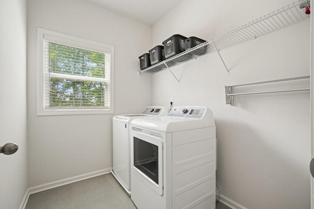 laundry room with laundry area, baseboards, light tile patterned floors, and washing machine and clothes dryer