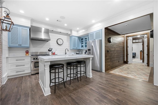 61 Alden Ave NW, Atlanta, GA 30309 - kitchen with appliances with stainless steel finishes, wall chimney range hood, a kitchen bar, a kitchen island with sink, and glass insert cabinets