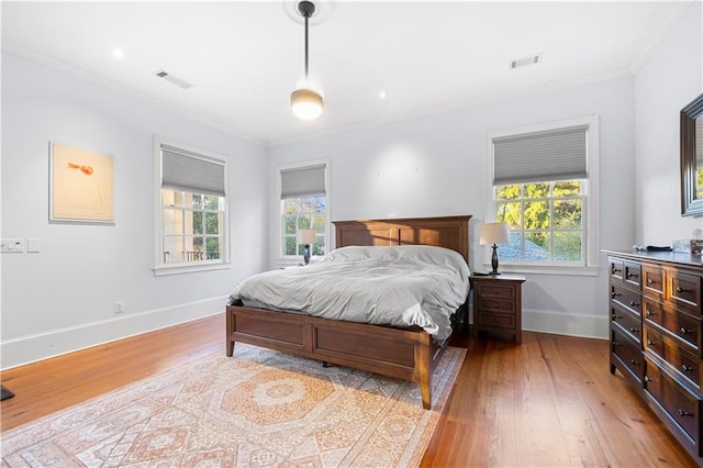 bedroom featuring multiple windows, crown molding, and light hardwood / wood-style floors