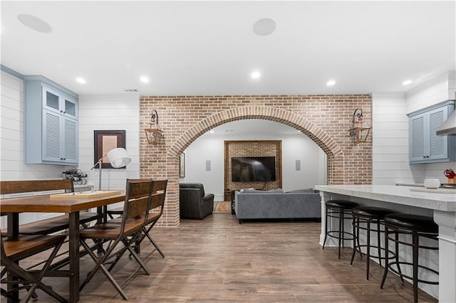 dining room featuring brick wall, arched walkways, dark wood-style flooring, and recessed lighting