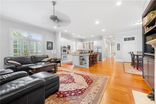 living room with crown molding, sink, ceiling fan, and light hardwood / wood-style flooring