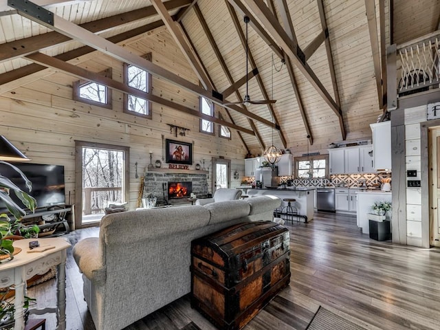 living room with dark wood-type flooring, wood walls, wooden ceiling, a fireplace, and ceiling fan with notable chandelier