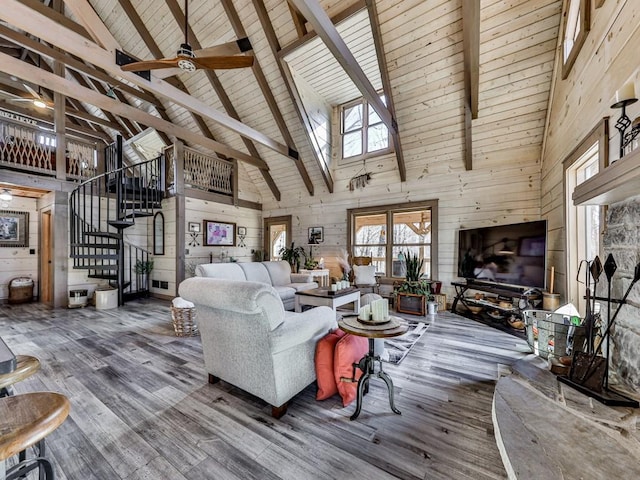 unfurnished living room with hardwood / wood-style flooring, beamed ceiling, ceiling fan, and wood walls