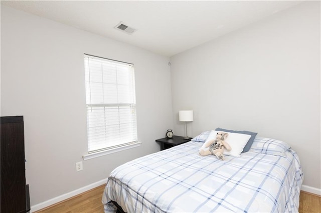 bedroom featuring baseboards, light wood-style flooring, and visible vents