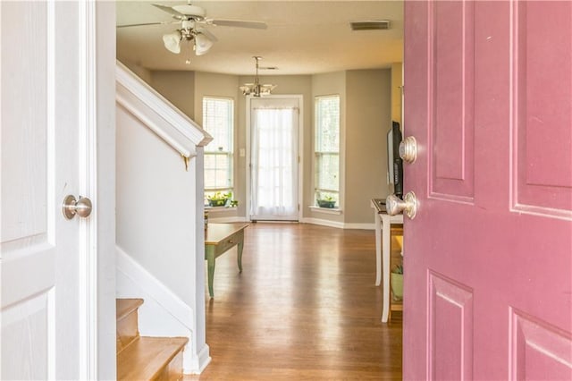 entryway with ceiling fan, visible vents, wood finished floors, baseboards, and stairs