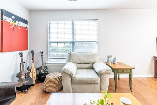 living area featuring baseboards, light wood finished floors, and visible vents