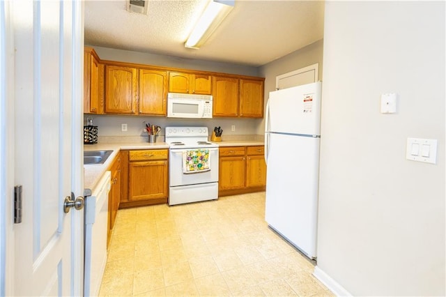 kitchen with visible vents, light countertops, brown cabinetry, and white appliances