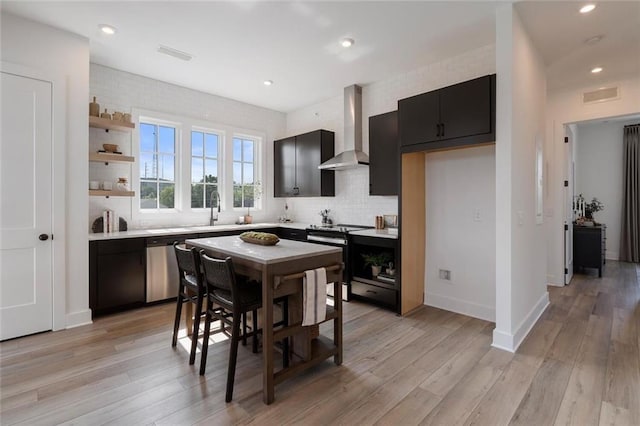 kitchen with wall chimney exhaust hood, range with electric stovetop, backsplash, and light hardwood / wood-style flooring