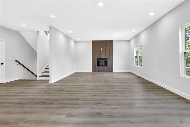 unfurnished living room featuring a healthy amount of sunlight, a fireplace, and light hardwood / wood-style flooring