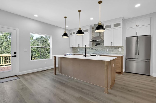 kitchen featuring stainless steel fridge, plenty of natural light, white cabinets, and a kitchen island with sink