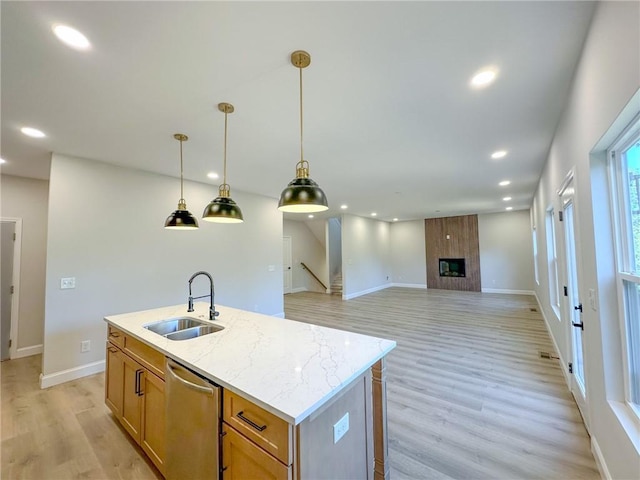 kitchen featuring a large fireplace, dishwasher, sink, an island with sink, and decorative light fixtures