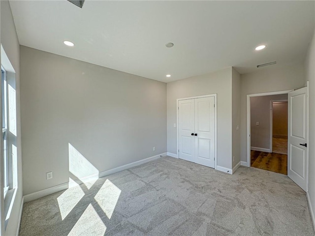 unfurnished bedroom with a closet and light colored carpet