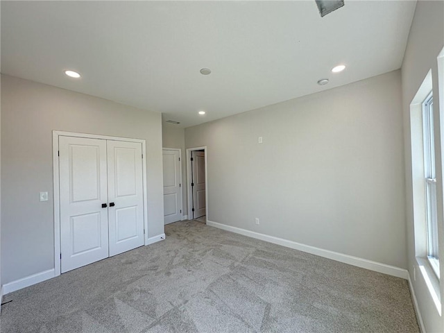 unfurnished bedroom featuring light colored carpet and a closet