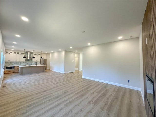 unfurnished living room with light hardwood / wood-style flooring and sink