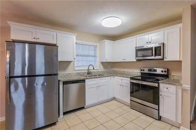 kitchen with white cabinets, light stone counters, sink, and appliances with stainless steel finishes