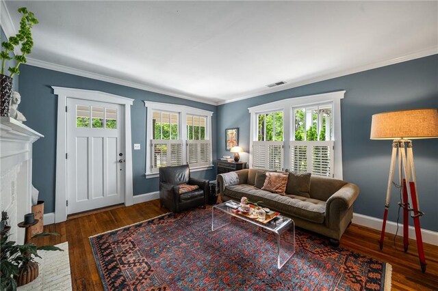 living area featuring crown molding, baseboards, wood finished floors, and visible vents