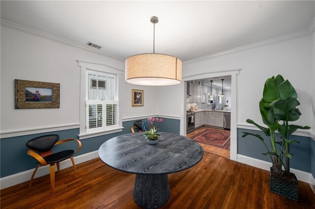 dining space with crown molding, baseboards, visible vents, and wood finished floors