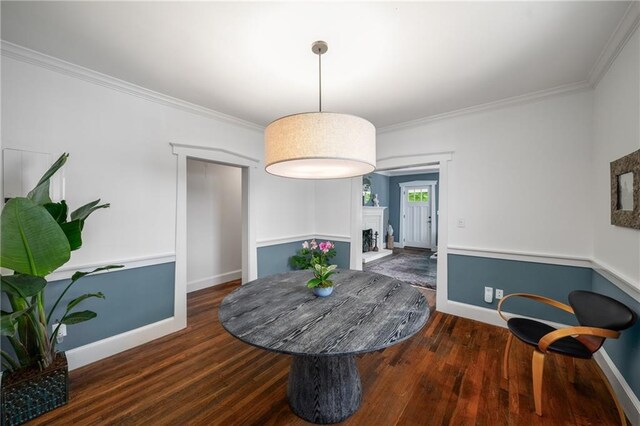 dining area featuring a fireplace with raised hearth, baseboards, and wood finished floors