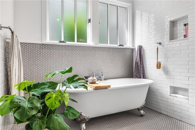 bathroom featuring a freestanding tub, tile patterned floors, and tile walls