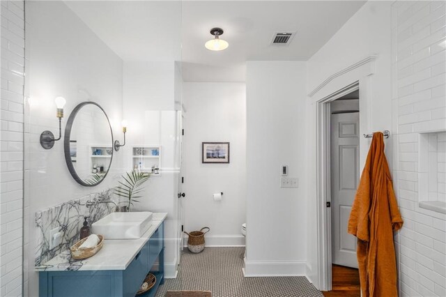 bathroom with tile patterned flooring, vanity, toilet, baseboards, and visible vents