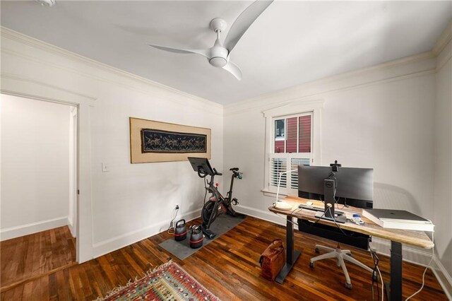 office space featuring baseboards, ceiling fan, ornamental molding, and wood finished floors