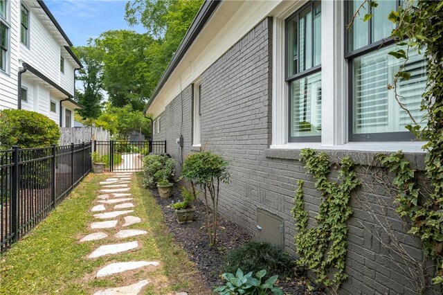 view of side of property with brick siding, fence, and crawl space