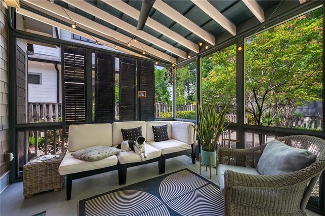 sunroom featuring beamed ceiling, plenty of natural light, and an outdoor hangout area
