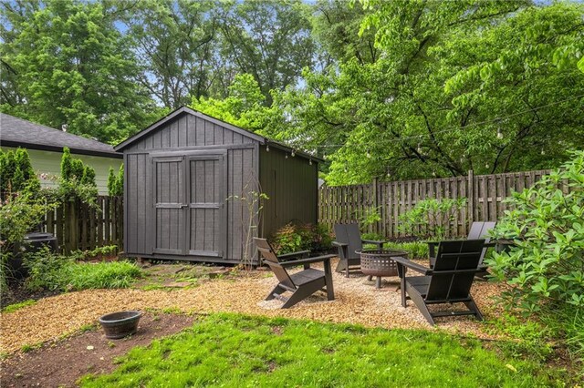 view of shed with a fenced backyard and a fire pit