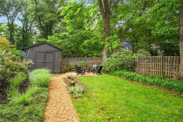 view of yard featuring fence, an outdoor structure, an outdoor fire pit, and a shed