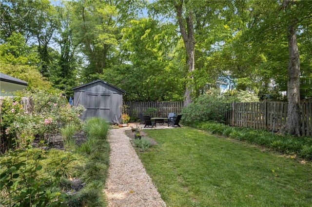 view of yard with a fenced backyard, a shed, a patio area, an outdoor fire pit, and an outbuilding