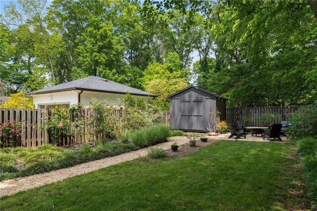 view of yard with a fenced backyard, an outbuilding, and a storage shed