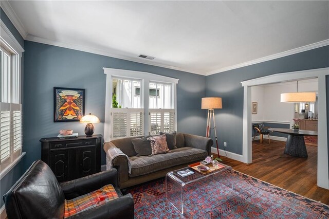 living area featuring crown molding, baseboards, a healthy amount of sunlight, and wood finished floors