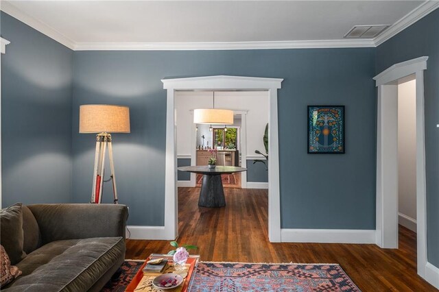 living room featuring baseboards, visible vents, ornamental molding, and wood finished floors